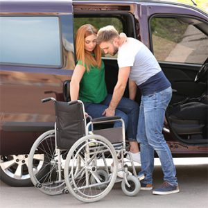 גבר מסייע לאשה לעבור מרכב לכסא גלגלים